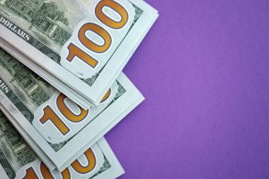 Mor arka planda büyük miktarda yüz dolarlık banknotlar. ABD 'de vergilendirme ve para yapma kavramı