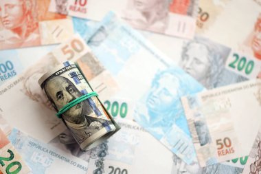 Bir tomar Amerikan doları büyük miktarda Brezilya banknotlarının üzerinde yatıyor. Amerikan parası Brezilya 'nın para akışında yatıyor. Brezilya 'da ekonomi ve döviz kuru kavramı