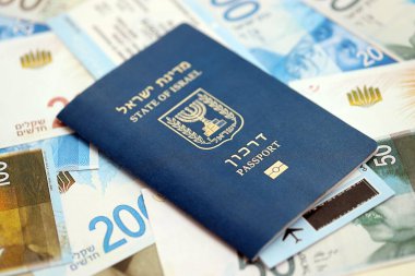 Israel New Shekels banknotları ve pasaportu. İsrail 'in mevcut para faturaları ve biyometrik geçiş kartı büyük miktarda masada yatıyor. İsrail 'de seyahat ve tatil kavramı