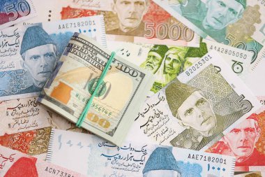 Bir sürü Amerikan doları Pakistan Rupileri 'nin banknotlarına yakın duruyor. Amerikan para demeti Pakistan 'ın para banknotlarında yatıyor. Pakistan 'da ekonomi ve döviz kuru kavramı