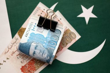 Pakistan bayrağı üzerinde Pakistan banknotları. Pakistan 'ın mevcut para faturaları büyük miktarlarda pankartta yatıyor. Pakistan 'da ekonomi ve ticaret kavramı
