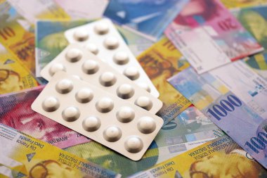 İsviçre frangı ve ilaç hapları. Mevcut para ve uyuşturucu banknotları büyük miktarda masada yatıyor. İsviçre 'de ilaç ve eczane kavramı