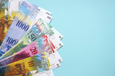 Mavi arka planda İsviçre frangı banknotları. Mevcut frank para faturaları büyük miktarda masada yatıyor. İsviçre 'de iş ve yatırım kavramı