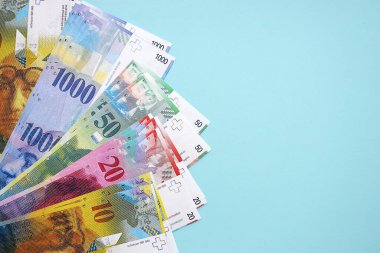 Mavi arka planda İsviçre frangı banknotları. Mevcut frank para faturaları büyük miktarda masada yatıyor. İsviçre 'de iş ve yatırım kavramı