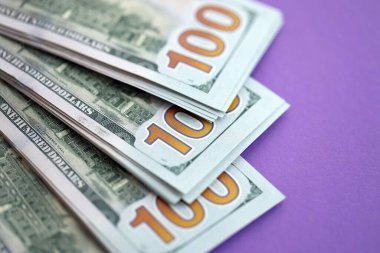 Mor arka planda büyük miktarda yüz dolarlık banknotlar. ABD 'de vergilendirme ve para yapma kavramı