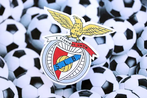 KYIV, UKRAINE - 23 Şubat 2025 Sport Lisboa ve Benfica futbol kulübü rozeti futbol topu arka plan afişinde yatıyor
