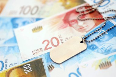 İsrail Yeni Şekelleri 'nin banknotları ve askeri simgesi. İsrail 'in mevcut para faturaları ve künyeleri büyük miktarda masada yatıyor. İsrail 'de askerlik kavramı
