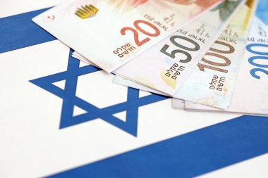 Israel New Shekels banknotları ulusal bayrak üzerinde. İsrail 'in şu anki para faturaları büyük oranda bayrağın üzerinde yatıyor. İsrail 'de iş ve yatırım kavramı