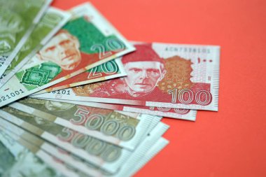 Pakistan kırmızı arka planda banknotlar halinde. Pakistan 'ın mevcut para faturaları büyük miktarda masada yatıyor. Pakistan 'da iş ve yatırım kavramı