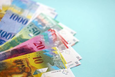 Mavi arka planda İsviçre frangı banknotları. Mevcut frank para faturaları büyük miktarda masada yatıyor. İsviçre 'de iş ve yatırım kavramı