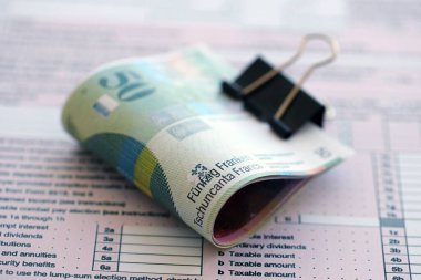 İsviçre frangı banknotları ve vergi formu. Mevcut para faturaları vergi iade formunda yatıyor. İsviçre 'de vergilendirme kavramı