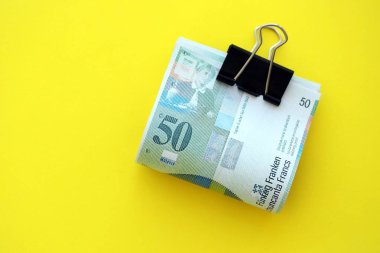 Sarı arka planda İsviçre frangı banknotları. Mevcut frank para faturaları büyük miktarda masada yatıyor. İsviçre 'de iş ve yatırım kavramı