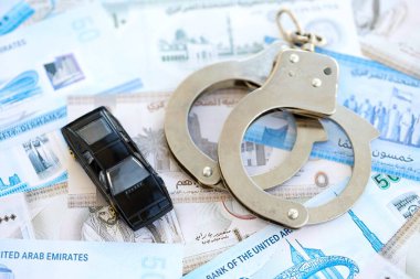 Birleşik Arap Emirlikleri kara para birimi faturaları ve kelepçeli oyuncak araba. Araba kazası kavramı.