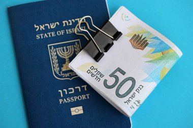 Israel New Shekels banknotları ve mavi arka planda pasaport. İsrail 'in şu anki para banknotları büyük oranda mavi üzerine yatar. İsrail 'de finans ve nakit kavramı