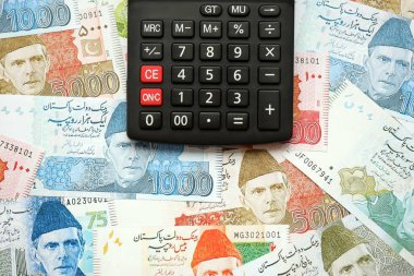 Pakistan banknotları ve hesap makinesi. Pakistan 'ın mevcut para ve hesap makinesi büyük miktarda masada yatıyor. Pakistan 'da vergi ve para sayımı kavramı