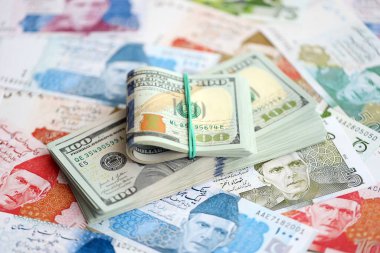 Amerikan dolarları yığını Pakistan Rupi banknotlarının büyük bir miktarına yakın duruyor. Amerikan para demeti Pakistan 'ın para banknotlarında yatıyor. Pakistan 'da ekonomi ve döviz kuru kavramı