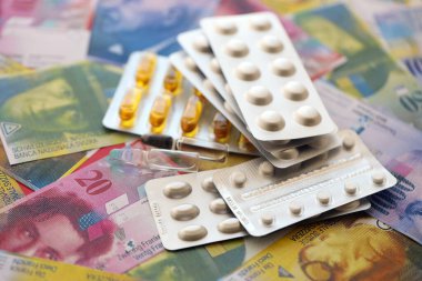 İsviçre frangı ve ilaç hapları. Mevcut para ve uyuşturucu banknotları büyük miktarda masada yatıyor. İsviçre 'de ilaç ve eczane kavramı