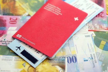 İsviçre frangı banknotları ve biletli pasaport. Mevcut banknotlar ve biyometrik geçiş kartları büyük miktarda masada yatıyor. İsviçre 'de seyahat ve tatil kavramı