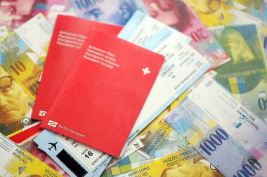 İsviçre frangı banknotları ve biletli pasaport. Mevcut banknotlar ve biyometrik geçiş kartları büyük miktarda masada yatıyor. İsviçre 'de seyahat ve tatil kavramı