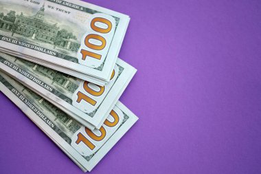 Mor arka planda büyük miktarda yüz dolarlık banknotlar. ABD 'de vergilendirme ve para yapma kavramı