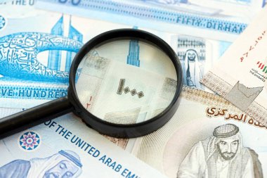 Birleşik Arap Emirlikleri kara para birimi banknotları ve büyüteç yakın çekim. Finansal izleme ve vergilendirme kavramı