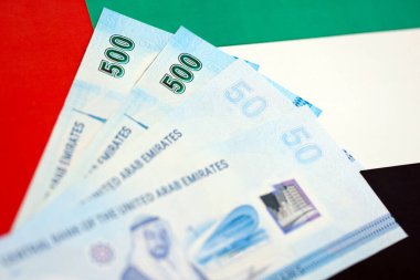 Birleşik Arap Emirlikleri kara para birimi banknotları bayrağa yakın duruyor. İş ve yatırım kavramı