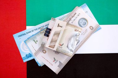 Birleşik Arap Emirlikleri kara para birimi banknotları bayrağa yakın duruyor. İş ve yatırım kavramı