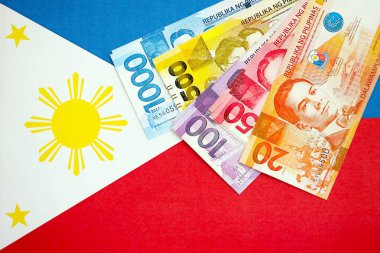 Filipinler Peso para birimi banknotları bayrağın üzerinde duruyor. İş ve yatırım kavramı