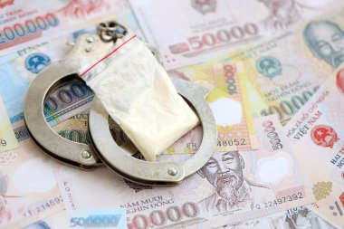 Vietnam dong para birimi faturaları ve kelepçeli kokain paketi. Uyuşturucu suçları kavramı