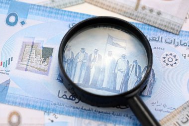 Birleşik Arap Emirlikleri kara para birimi banknotları ve büyüteç yakın çekim. Finansal izleme ve vergilendirme kavramı