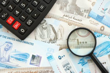 Birleşik Arap Emirlikleri kara para birimi faturaları ve büyüteçle yakınlaştırılmış hesap makinesi. Vergilendirme ve para sayımı kavramı