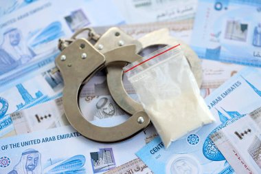 Birleşik Arap Emirlikleri kara para birimi faturaları ve kelepçeli kokain paketleri. Uyuşturucu suçları kavramı