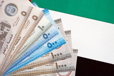 Birleşik Arap Emirlikleri kara para birimi banknotları bayrağa yakın duruyor. İş ve yatırım kavramı