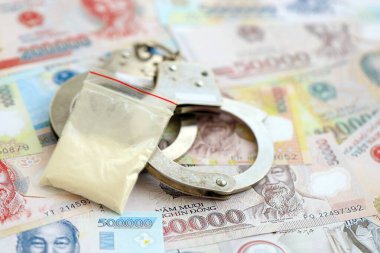 Vietnam dong para birimi faturaları ve kelepçeli kokain paketi. Uyuşturucu suçları kavramı
