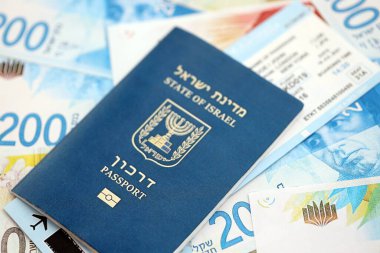 Israel New Shekels banknotları ve pasaportu. İsrail 'in mevcut para faturaları ve biyometrik geçiş kartı büyük miktarda masada yatıyor. İsrail 'de seyahat ve tatil kavramı