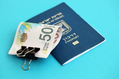 Israel New Shekels banknotları ve mavi arka planda pasaport. İsrail 'in şu anki para banknotları büyük oranda mavi üzerine yatar. İsrail 'de finans ve nakit kavramı