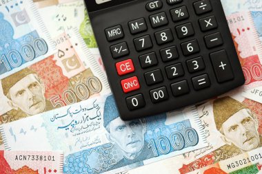 Pakistan banknotları ve hesap makinesi. Pakistan 'ın mevcut para ve hesap makinesi büyük miktarda masada yatıyor. Pakistan 'da vergi ve para sayımı kavramı