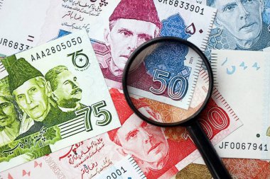 Pakistan banknotları ve büyüteç. Pakistan 'ın mevcut para ve büyüteç faturaları büyük miktarda masanın üzerinde duruyor. Pakistan 'da mali izleme ve vergilendirme kavramı