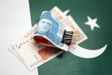 Pakistan bayrağı üzerinde Pakistan banknotları. Pakistan 'ın mevcut para faturaları büyük miktarlarda pankartta yatıyor. Pakistan 'da ekonomi ve ticaret kavramı