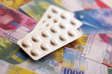 İsviçre frangı ve ilaç hapları. Mevcut para ve uyuşturucu banknotları büyük miktarda masada yatıyor. İsviçre 'de ilaç ve eczane kavramı