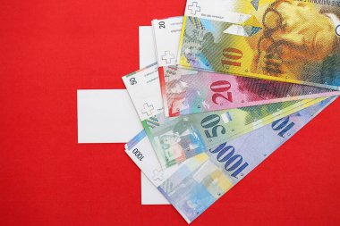 İsviçre frangı banknotları ve bayrağı. Mevcut para banknotları büyük miktarda bayrağın üzerinde yatıyor. İsviçre 'de iş ve yatırım kavramı