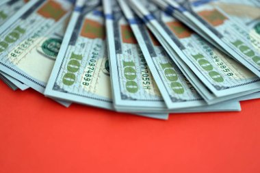 Kırmızı arka planda büyük miktarda yüz dolarlık banknot var. ABD 'de vergilendirme ve para yapma kavramı