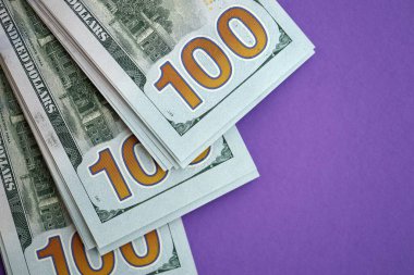 Mor arka planda büyük miktarda yüz dolarlık banknotlar. ABD 'de vergilendirme ve para yapma kavramı