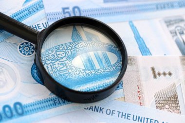 Birleşik Arap Emirlikleri kara para birimi banknotları ve büyüteç yakın çekim. Finansal izleme ve vergilendirme kavramı