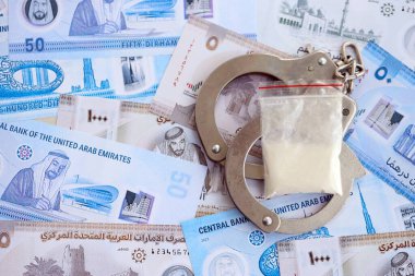 Birleşik Arap Emirlikleri kara para birimi faturaları ve kelepçeli kokain paketleri. Uyuşturucu suçları kavramı