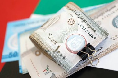 Birleşik Arap Emirlikleri kara para birimi banknotları bayrağa yakın duruyor. İş ve yatırım kavramı