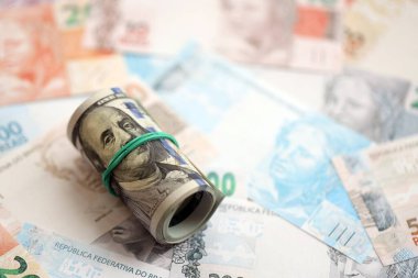 Bir tomar Amerikan doları büyük miktarda Brezilya banknotlarının üzerinde yatıyor. Amerikan parası Brezilya 'nın para akışında yatıyor. Brezilya 'da ekonomi ve döviz kuru kavramı