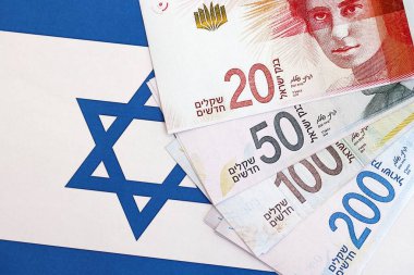 Israel New Shekels banknotları ulusal bayrak üzerinde. İsrail 'in şu anki para faturaları büyük oranda bayrağın üzerinde yatıyor. İsrail 'de iş ve yatırım kavramı