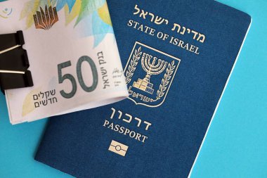 Israel New Shekels banknotları ve mavi arka planda pasaport. İsrail 'in şu anki para banknotları büyük oranda mavi üzerine yatar. İsrail 'de finans ve nakit kavramı