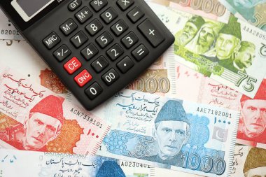 Pakistan banknotları ve hesap makinesi. Pakistan 'ın mevcut para ve hesap makinesi büyük miktarda masada yatıyor. Pakistan 'da vergi ve para sayımı kavramı